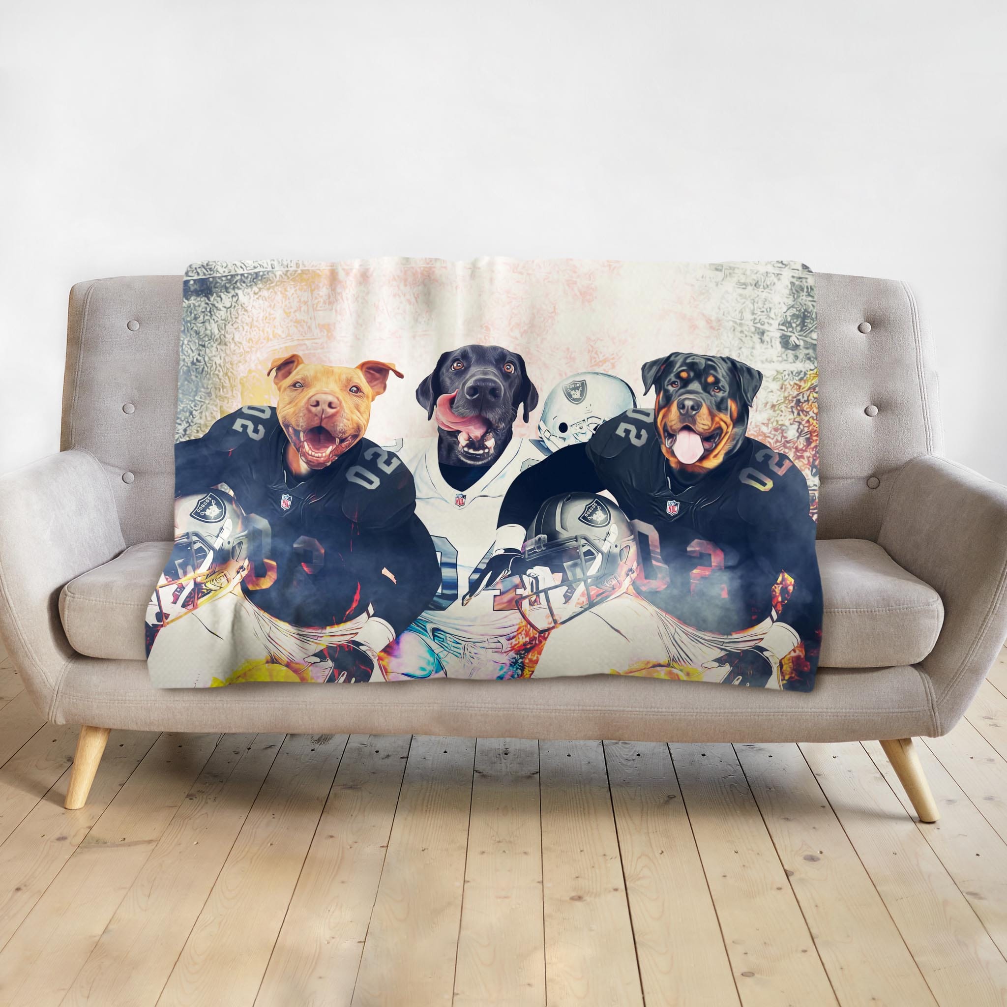 Personalized minky blanket with three dogs in football uniforms, draped over a gray sofa.