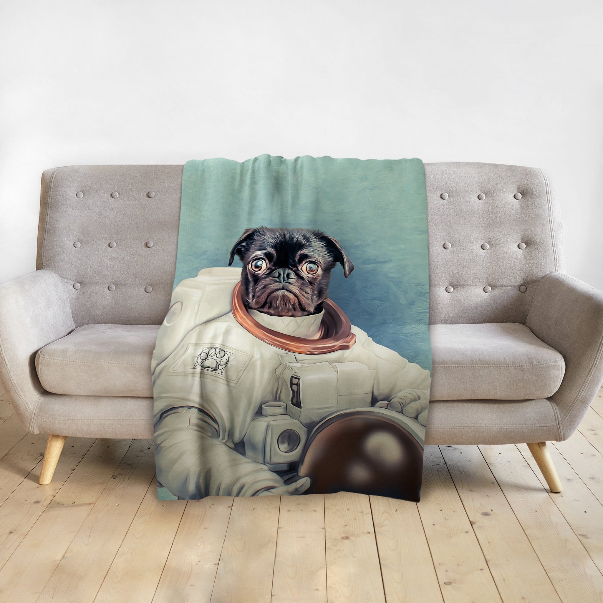 Personalized pet blanket with a black pug in an astronaut portrait design on a gray sofa.