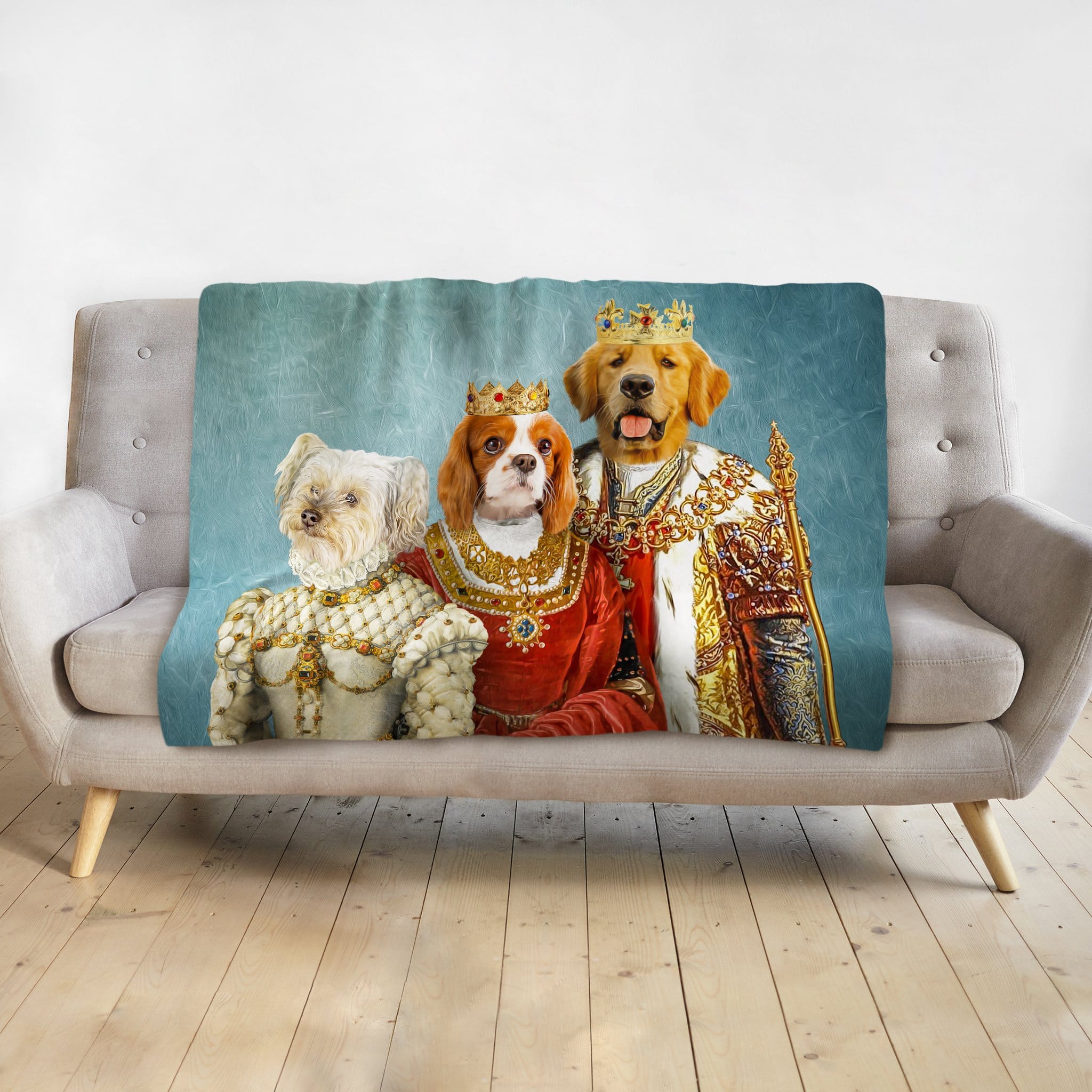 Personalized 3-pet royal renaissance portrait blanket on a couch, featuring a white dog, Cavalier King Charles, and Golden Retriever.