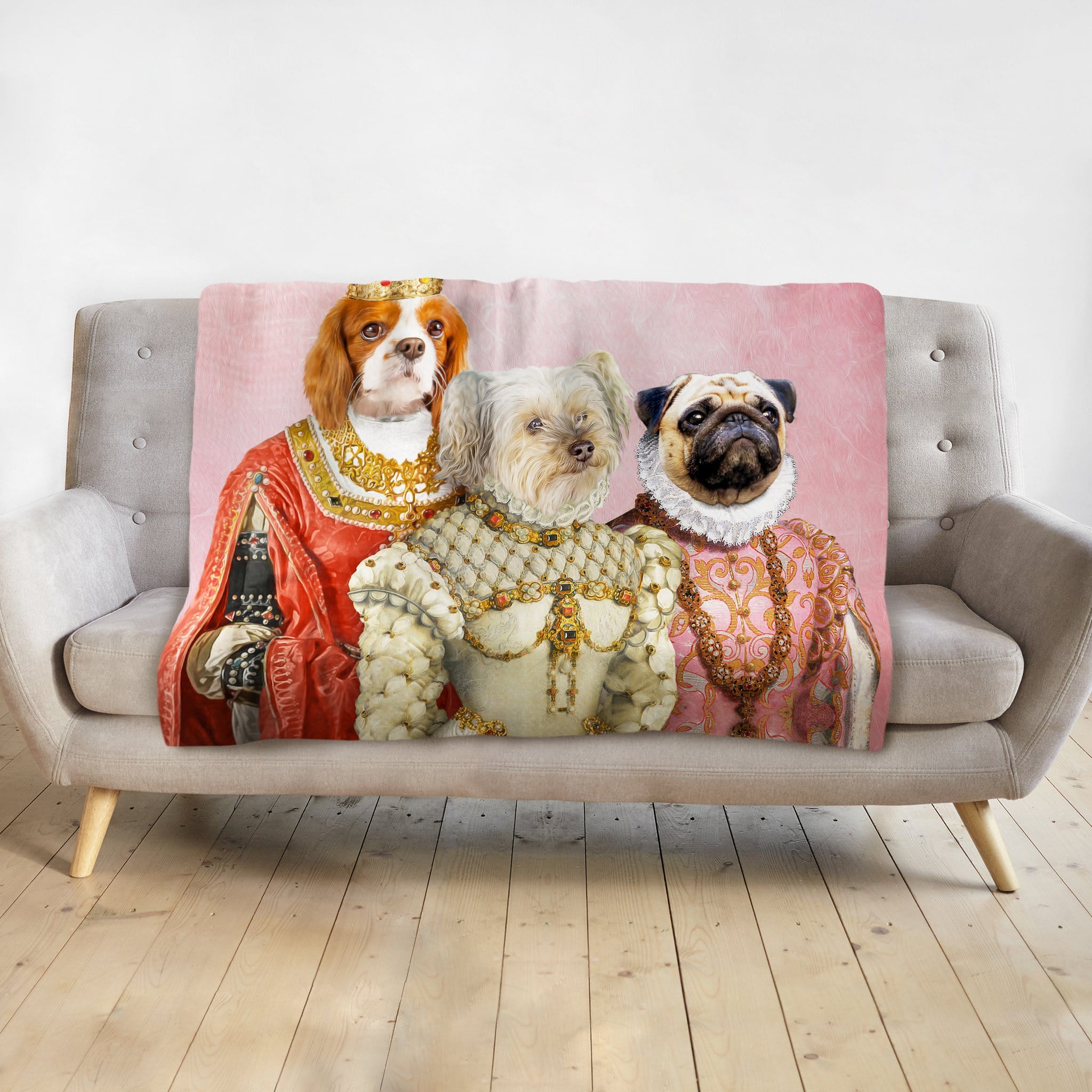 Personalized pink blanket with three dogs in royal renaissance portraits on a gray couch.