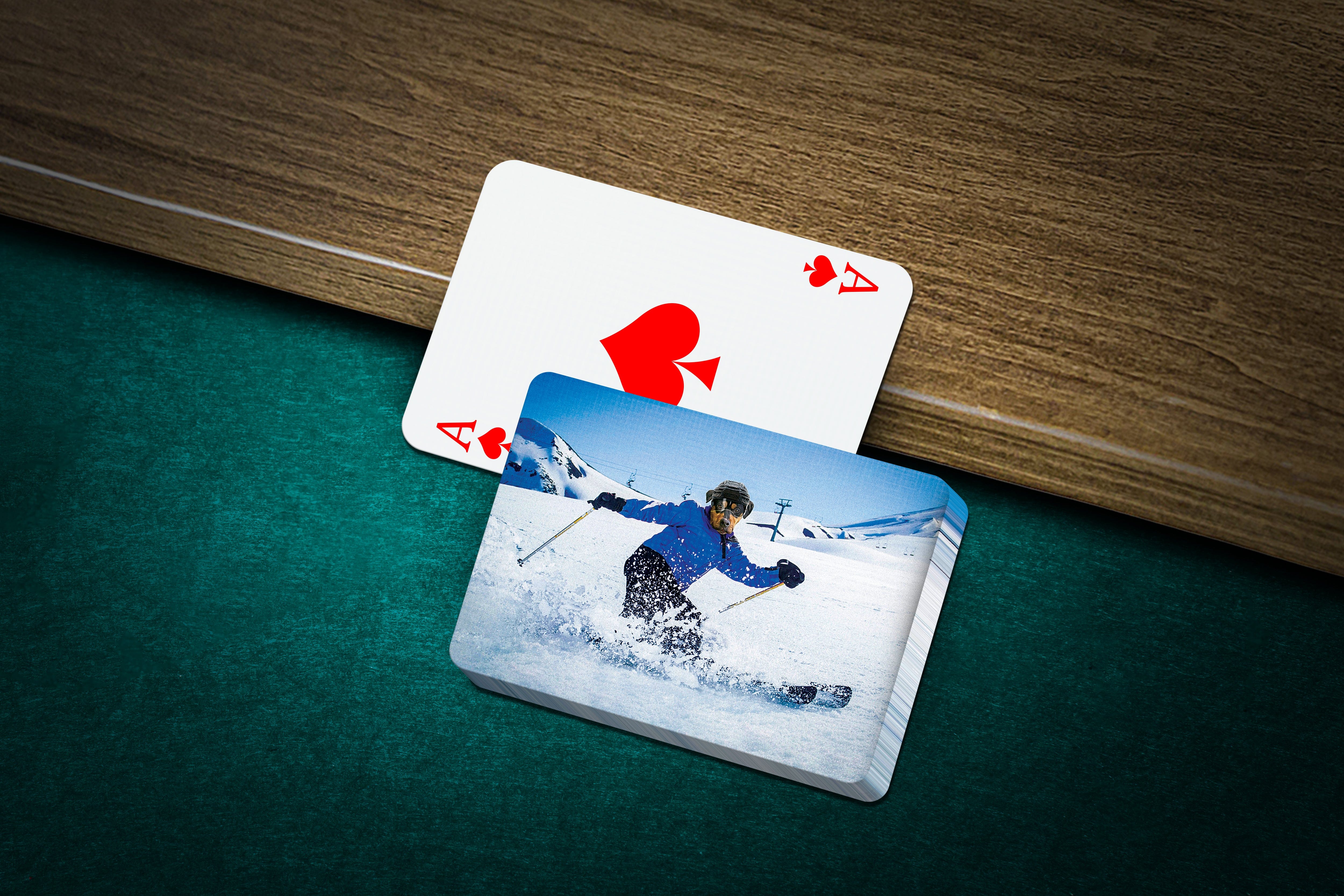 Personalized pet playing cards with a custom 'Skier' portrait design on a green felt table.