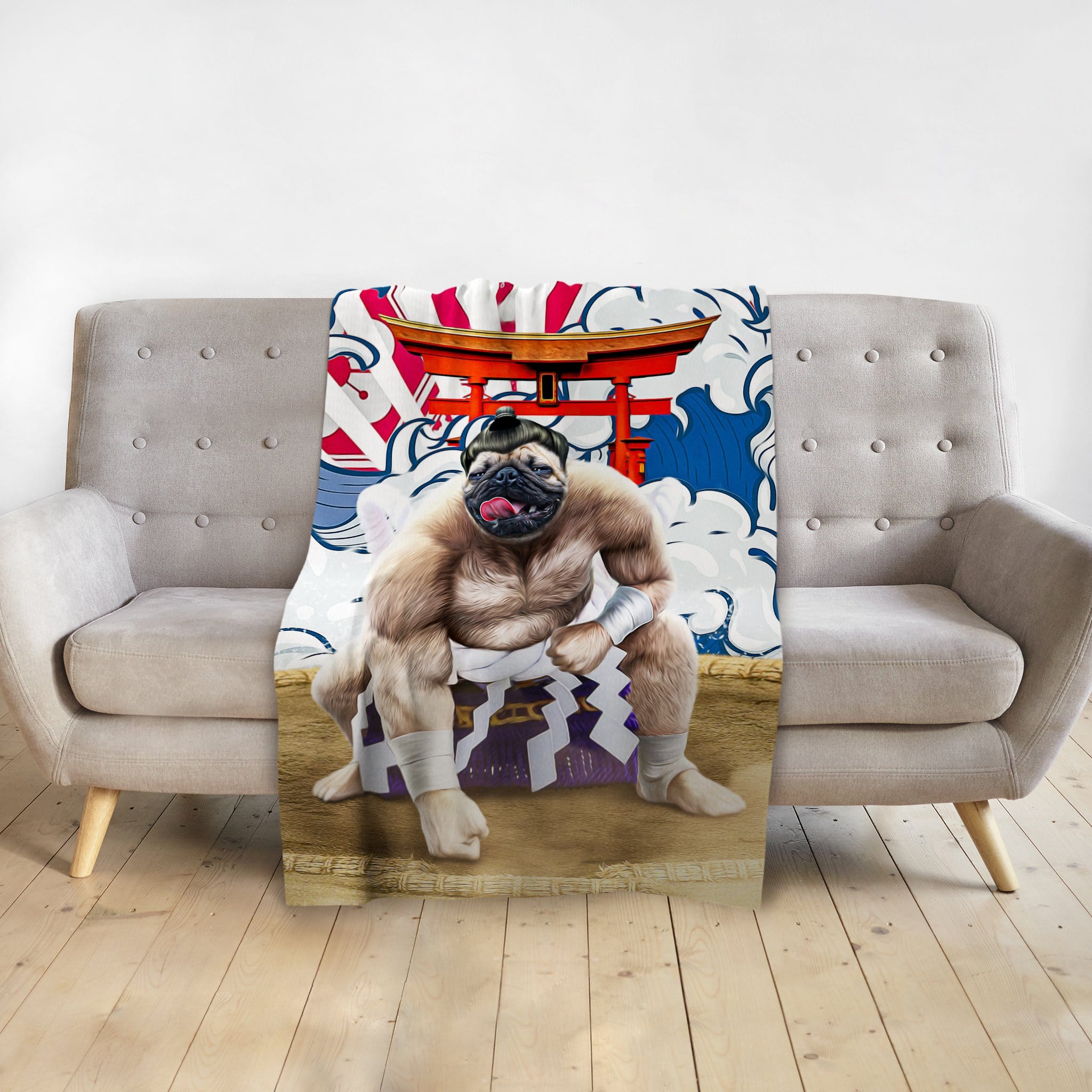 Personalized pet blanket with a pug in a sumo wrestler portrait, draped over a gray sofa.
